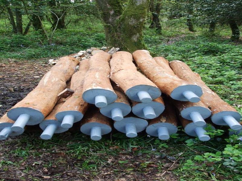 posts piled awaiting assembly, with integral cylindrical tenons on both ends of a round pole, painted for protection